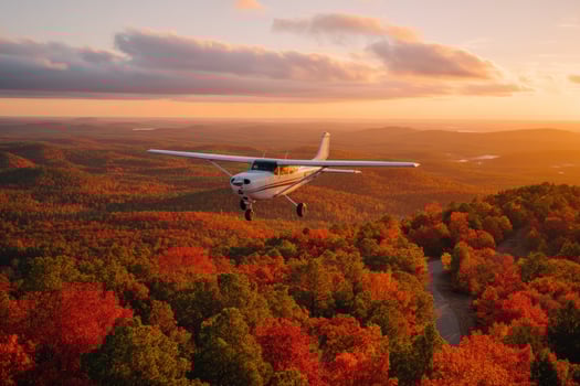 Small airplane flying over colorful autumn foliage at sunset with winding roads photo