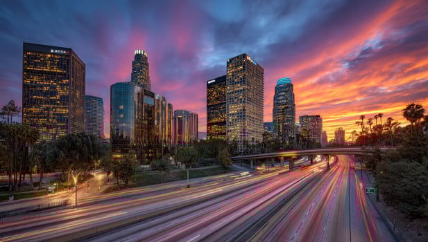 Cityscape at dusk traffic flows into downtown, warm sunset sky background photo