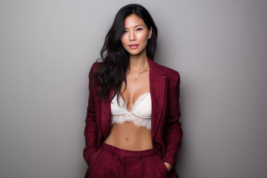 Confident young woman wearing maroon business suit in studio against gray backdrop photo