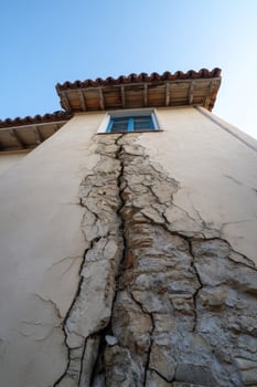 Cracked wall on old building, sky overhead on sunny day in town photo