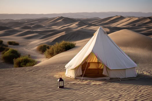 Desert Camping Tent and lantern near shrubs. Sand dunes roll to the horizon photo