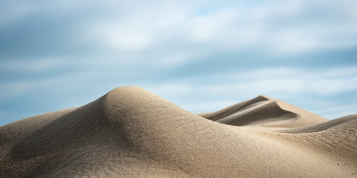 Desert landscape scene with sand dunes under a cloudy blue sky. For travel use photo