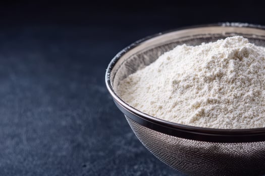 Powdered flour in metal sifter on dark surface, soft texture and fine particles ready for baking or cooking use photo