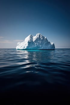 Iceberg floats on dark, cold sea waters, with blue sky. Tourism backdrop photo