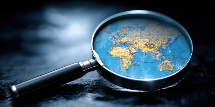 Magnifying glass over a map of Asia, studying global events on a dark surface photo