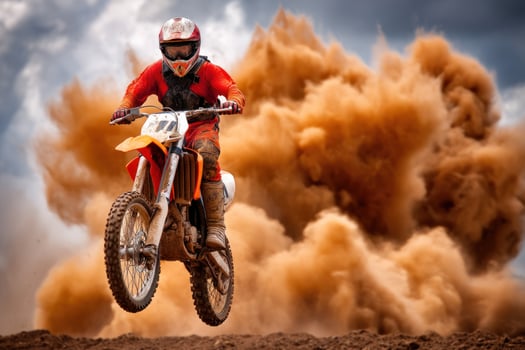 Motocross rider jumps during outdoor competition with dust and cloudy sky background photo