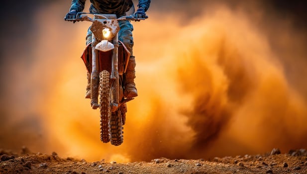 Motorcyclist leaps high into air amidst desert dust, showcasing extreme skill photo