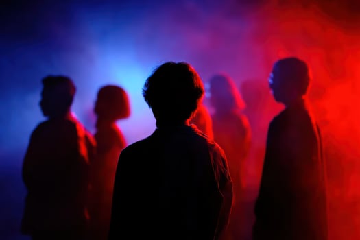 Silhouette of people standing in front of a red and blue light photo