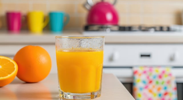 A glass of fresh orange juice with whole and sliced oranges photo