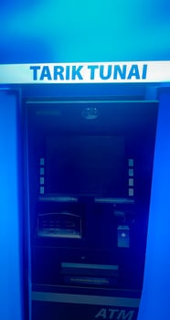 A blue lit close up shot of an Indonesian ATM machine with a glowing TARIK TUNAI Cash Withdrawal sign above, ready for customer use. photo