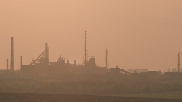 An Industrial Landscape at Dawn featuring Smokestacks and evident Pollution in the area photo
