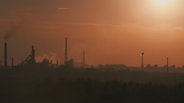 A mesmerizing Industrial Landscape at Sunset featuring Smokestacks and visible Pollution photo