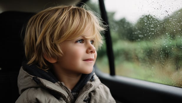 Boy looking out car window on a rainy day. Enjoying the ride in the countryside photo