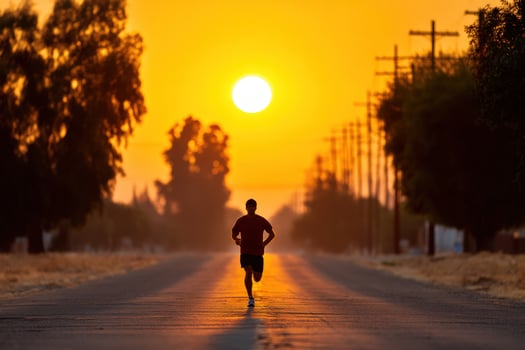 Athlete runs a road at sunset, framed by trees, background showing rural setting photo