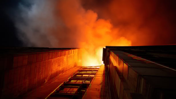 Building engulfed in intense flames, sky filled with smoke, dark nighttime background photo