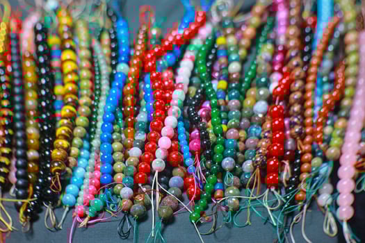 Vibrant handmade beaded bracelets arranged with colorful patterns at a Thai night market. Boho accessories blending spiritual beliefs with artisanal beauty. photo