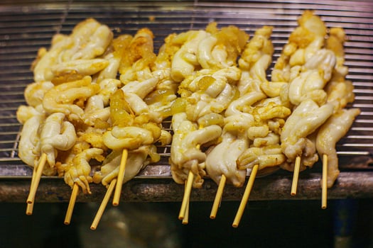 Grilled squid on skewers over charcoal fire at a Thai night market. Showcases Southeast Asian street food, gastro-tourism, and the vibrant appeal of local barbecue culture. photo
