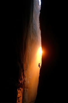 Climber rappelling down slot canyon as the sun sets on a outdoor adventure photo
