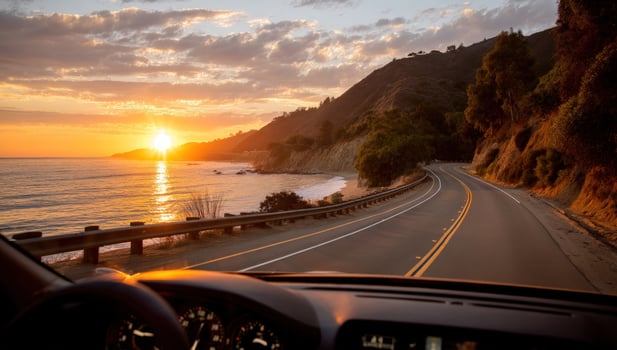 A car driving down a road with the sun setting in the distance photo