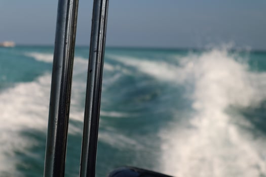 Boat tracks trace the bright turquoise sea, creating a foamy white pattern on the water's surface photo
