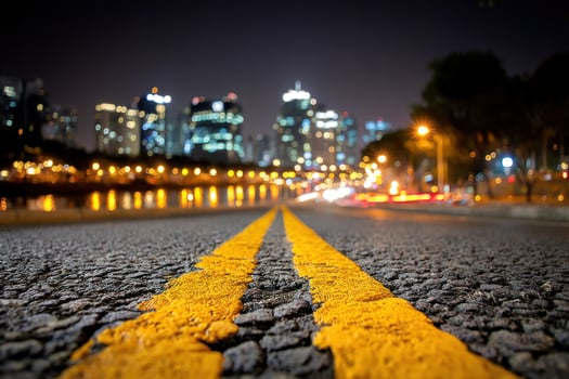 Yellow line on road at night with blurred city skyscrapers background photo