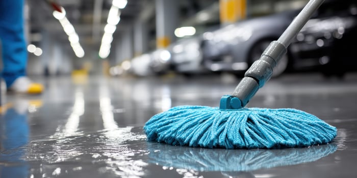 Janitor using mop cleaning floor inside car parking, maintenance service, hygiene photo
