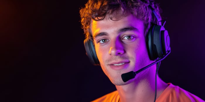 Young male gamer wearing headphones, focused on gaming, neon lights background photo