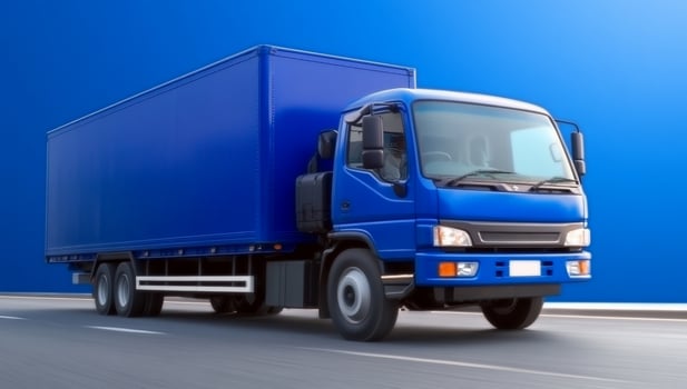Blue delivery truck driving on a highway against a vibrant blue background photo