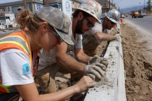 Three men and a woman working on a concrete wall photo