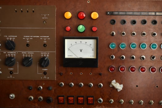 Old electronic dashboard featuring toggle switches, dials, and analog meters. Classic control interface for machines. photo