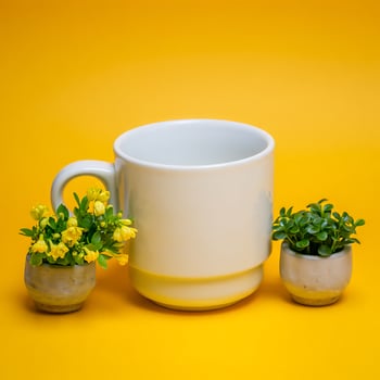 Bright yellow background with a white ceramic mug and small potted plants creating a cheerful and minimalist composition photo