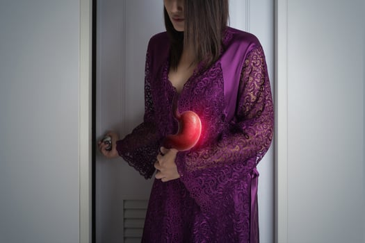 A woman clutching her stomach at night due to constipation. photo