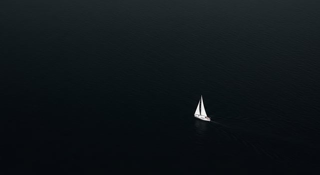 A sailboat is sailing in the dark ocean photo
