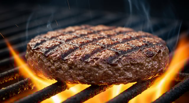A Thick, Juicy Beef Patty Sizzles on a Flaming Grill with Rising Smoke and Sparks photo