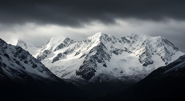 A snowy mountain range is seen under a dark sky photo