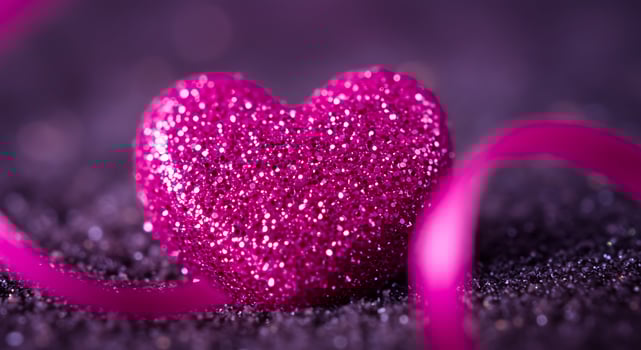 Luminous Magenta Glitter Heart with a Silky Ribbon on a Dark Purple Surface photo