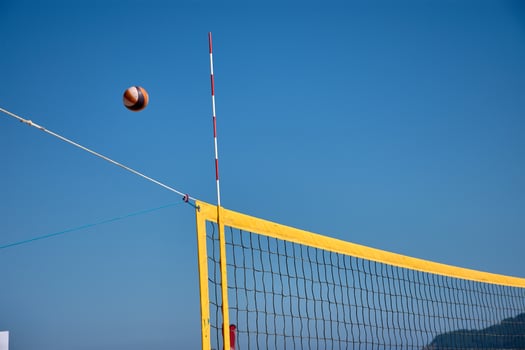 Active beach volleyball game with a ball crossing the yellow net during a sunny day on Baiona beach photo