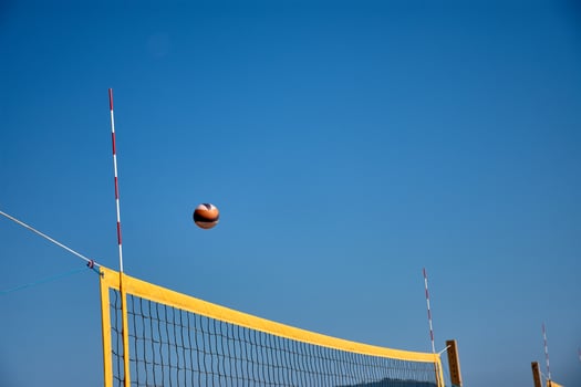 Beach volleyball match in Galicia with a ball moving over the net and a natural background of blue sky and mountains photo