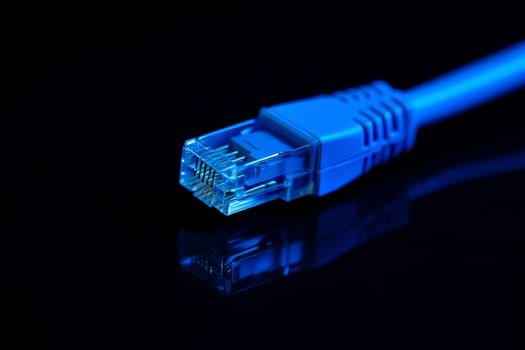 Close-up of blue ethernet cable connector on black surface, high-speed internet technology macro shot photo