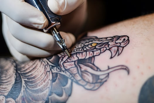 Tattoo artist carefully crafting detailed snake tattoo, realistic serpent with scales and fangs photo