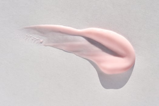 Smooth pink cream texture on white background with gentle lighting and minimalistic aesthetic. photo