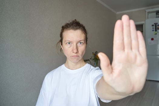 Caucasian female adult showing stop gesture with hand in indoor setting to convey refusal. photo