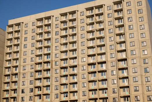 A sleek, modern apartment building stands prominently against a beautiful clear sky backdrop photo