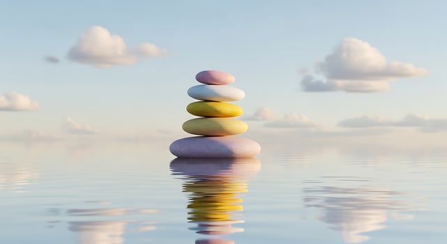 Balanced stones reflecting in water under a serene sky with soft clouds photo