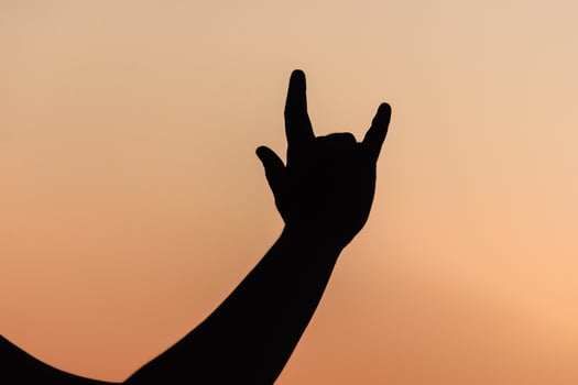 Silhouette of a hand making a rock-on sign, summer concert feeling. Celebrating life and music at sunset, freedom and joy.Celebrating life and music at sunset, freedom and joy. photo