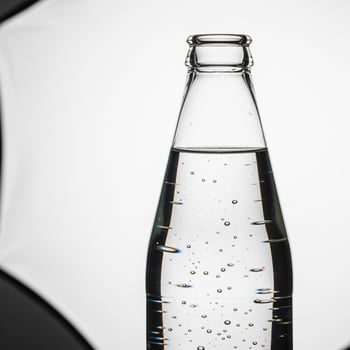 A bottle of soda with a black umbrella in the background photo