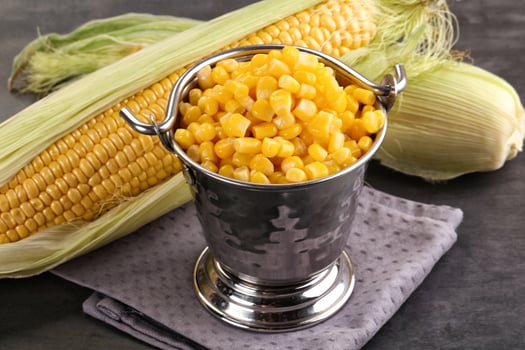 Corn in a metal bucket with a spoon photo