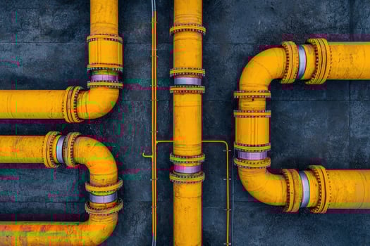 Yellow industrial pipes with metal joints and bolts on dark concrete wall, showing detailed texture and structure photo