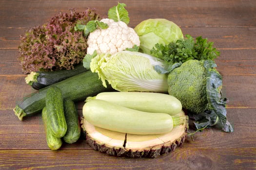 A lot of different fresh, green vegetables on a brown wooden background photo
