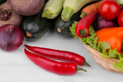 Many different vegetables include beets, cabbage, zucchini, carrots, tomatoes, peppers, onions, garlic, and cucumbers and lettuce on a white and wooden background. photo